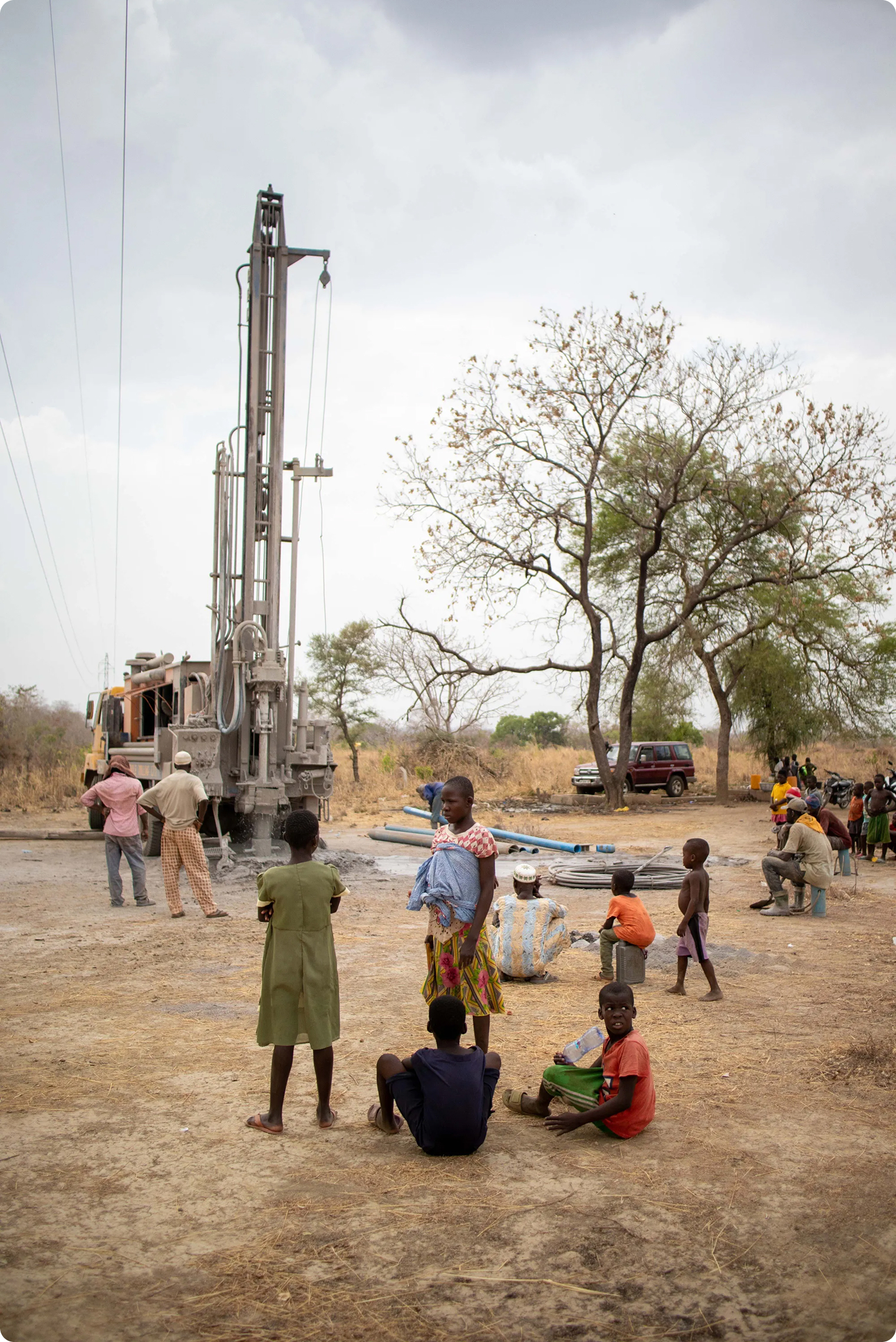 A large well drilling rig truck operating in a rural community under daylight