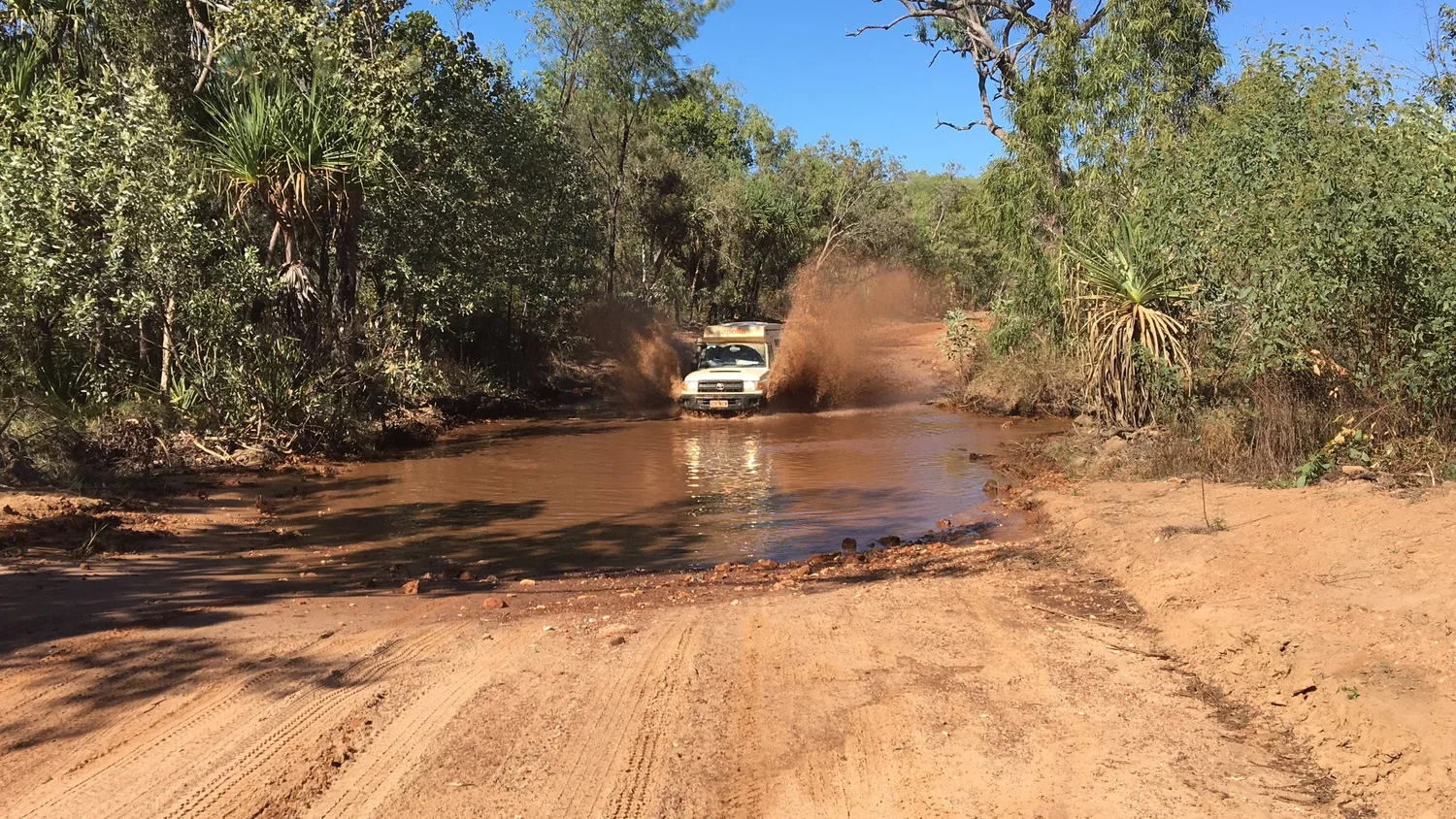 A pickup truck traveling down a remote rural dirt road in northern Ghana