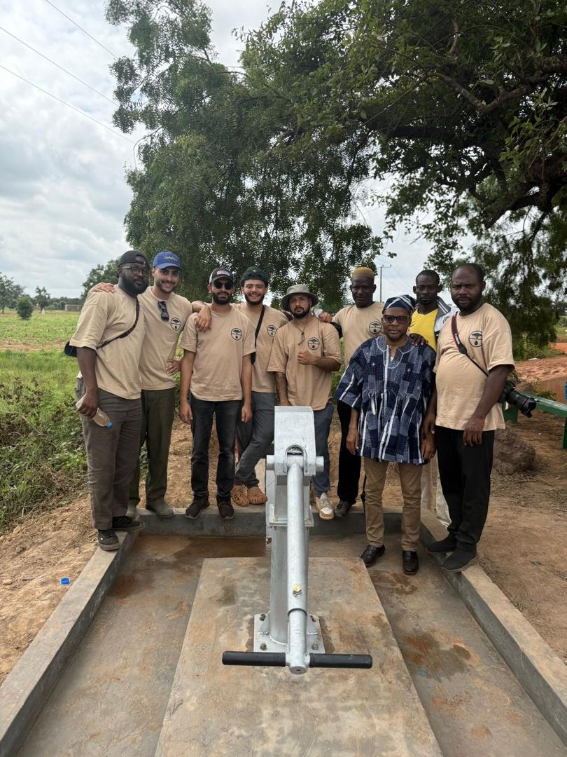 A researcher talking with local villagers near a borehole in northern Ghana